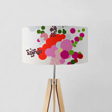 Load image into Gallery viewer, Contemporary drum lampshade with vibrant abstract floral design in red, pink, green, on a tripod lamp stand.