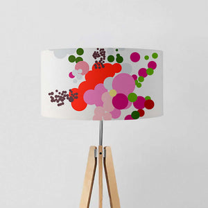 Contemporary drum lampshade with vibrant abstract floral design in red, pink, green, on a tripod lamp stand.