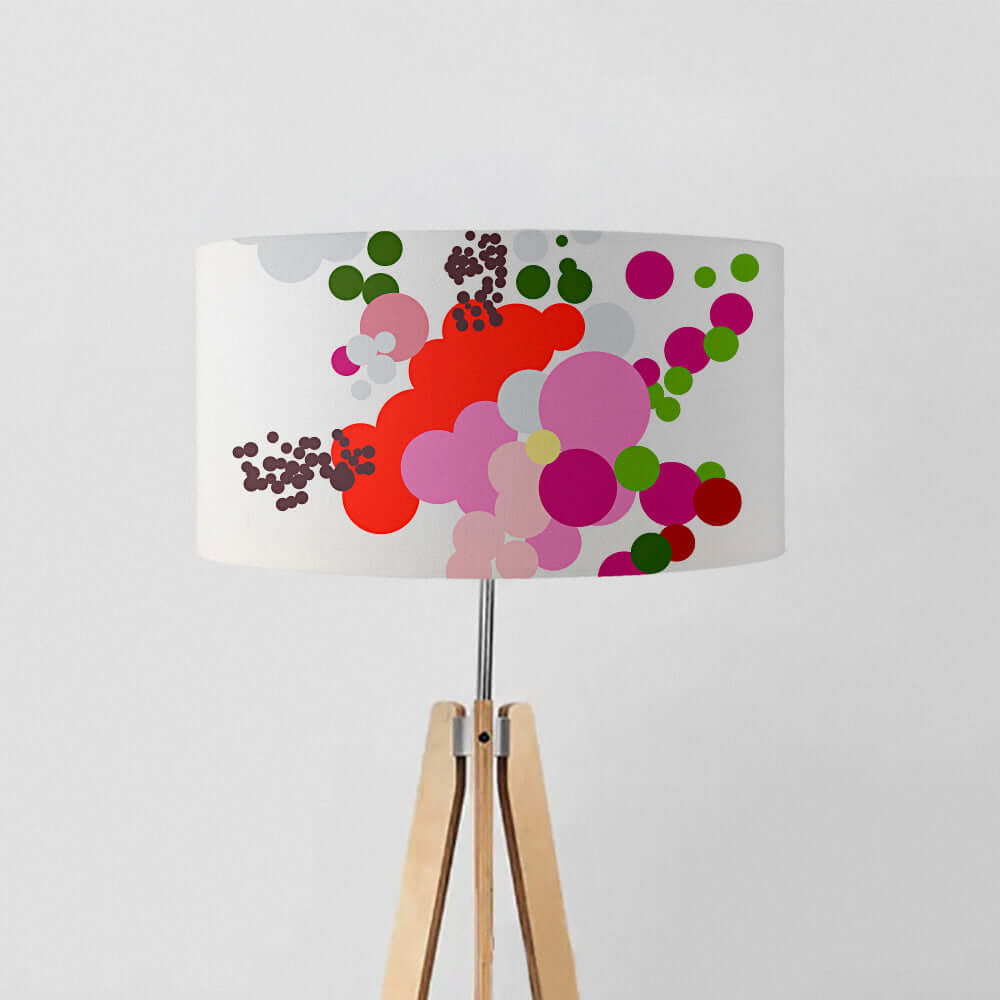 Contemporary drum lampshade with vibrant abstract floral design in red, pink, green, on a tripod lamp stand.