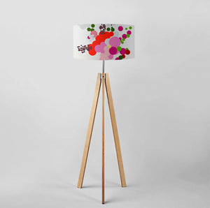 Red abstract floral drum lampshade on a wooden tripod floor lamp, showcasing vibrant colors and modern design.